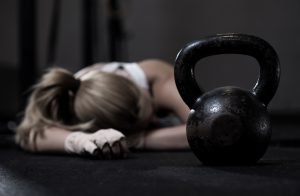 frau liegt nach crossfit workout am erschöpft am boden