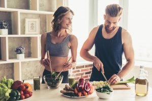 mann und frau kochen gesund in küche mit gemüse