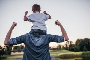 vater mit sohn auf der schulter spannen beide rücken an