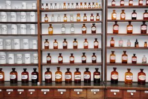 fläschchen und dosen im holzregal einer traditionellen apotheke