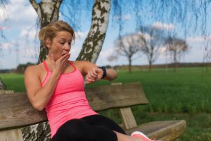 frau gähnt und guckt dabei auf fitnesstracker