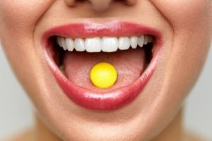 frau mit tablette im mund symbolbild antibiotika und sport