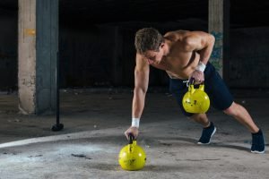 mann trainiert schulter mit kettlebells