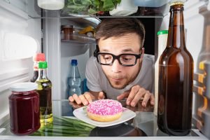 mann starrt auf donut in kühlschrank