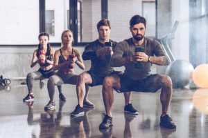 männer und frauen machen squats mit gewichten beim boxtraining