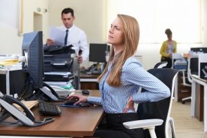 frau mit rückenschmerzen im büro