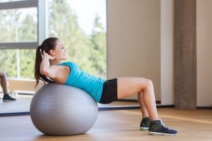 frau macht zuhause übung auf gymnastikball