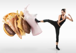 gesunde frau tritt burger pizza und milkshake weg symbolbild heilfasten