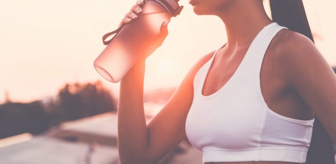 frau trinkt beim sport auf wasserflasche