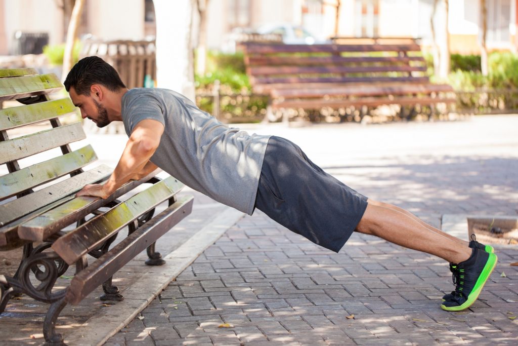 Mann macht Outdoor Fitness auf Parkbank