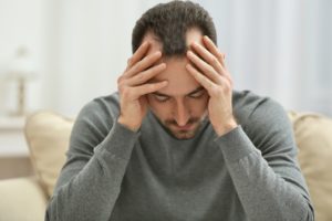 Mann mit Kopfschmerzen in depressiver Stimmung