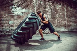 Mann hebt reifen beim schnellkrafttraining