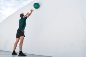 Mann wirft Medizinball gegen Wand