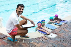 kinder lernen in einem schwimmkurs gemeinsam schwimmen